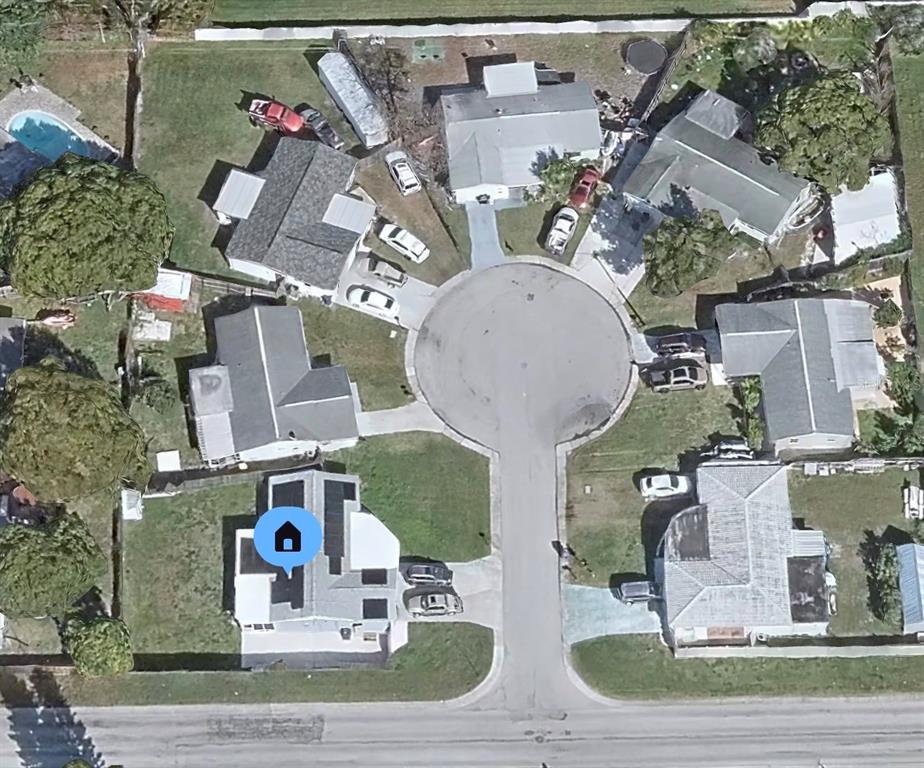 This aerial view shows a suburban cul-de-sac with several single-family homes and driveways — 2705 GARDNER PLACE, HOLIDAY, FL