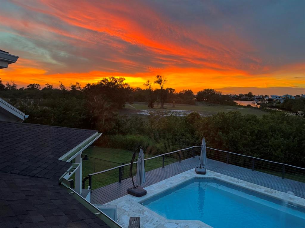 An elevated view of a backyard swimming pool and deck overlooking a sunset landscape — 945 BUNKER VIEW DRIVE, APOLLO BEACH, FL
