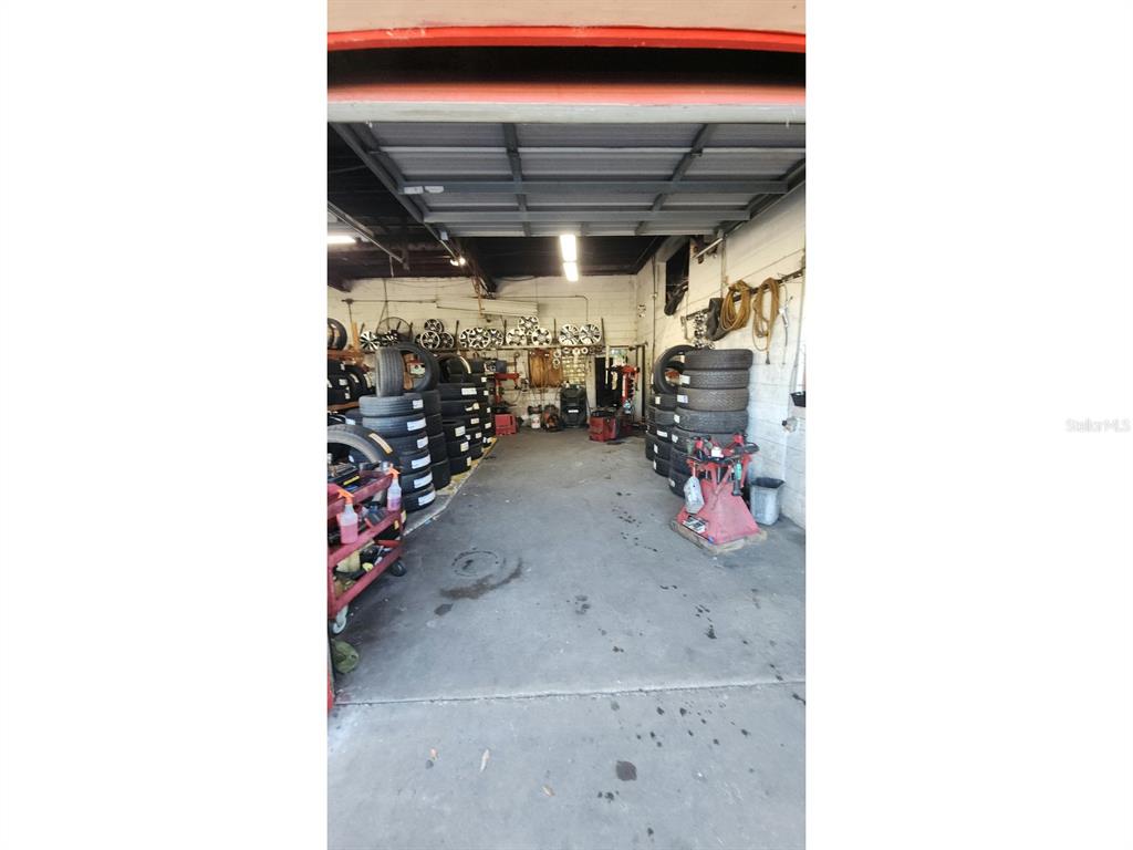 An auto repair shop interior features stacks of tires, automotive equipment, and wall-mounted wheel rims — 3515 N US HIGHWAY 17, DELAND, FL