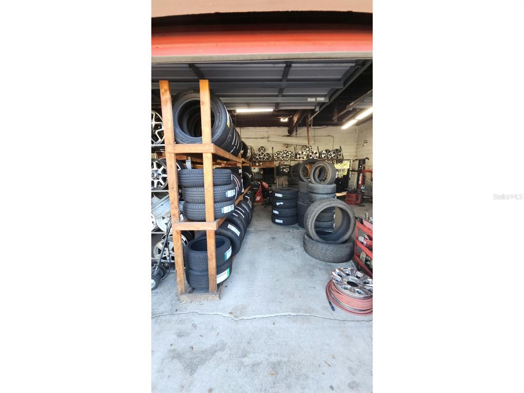 A garage interior features wooden shelving units stacked with numerous tires and automotive wheels — 3515 N US HIGHWAY 17, DELAND, FL