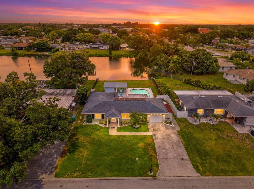 An aerial view of a single-story house with a pool, driveway, and backyard lake — 4822 60TH WAY N, KENNETH CITY, FL