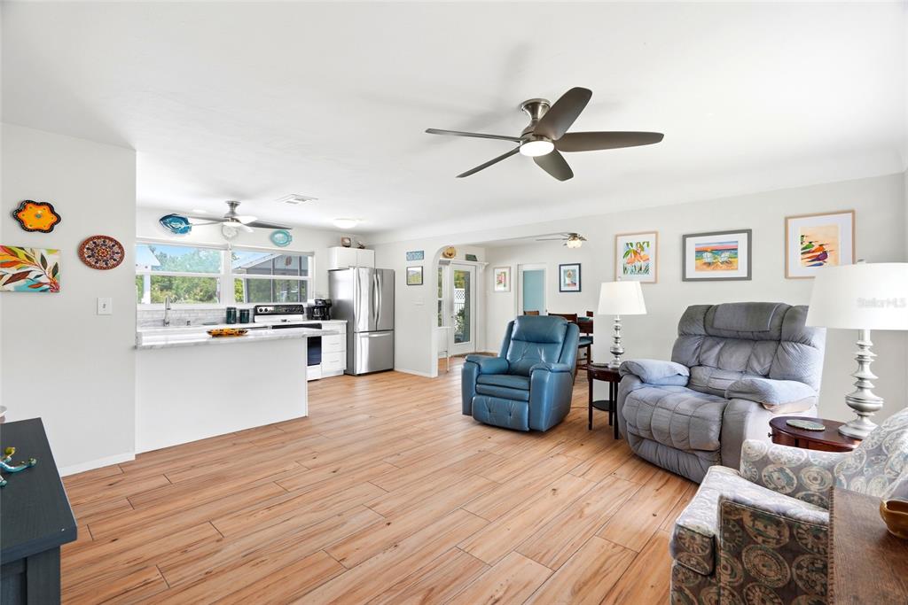 An open-concept living room and kitchen feature wood-look tile flooring and a ceiling fan — 4822 60TH WAY N, KENNETH CITY, FL