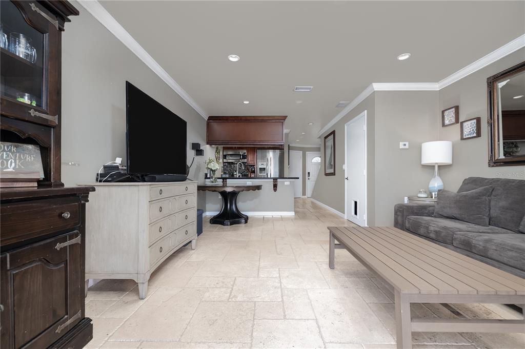A living room with tile flooring, a grey sofa, and an open kitchen area — 2470 OCEAN SHORE BOULEVARD UNIT 105, ORMOND BEACH, FL