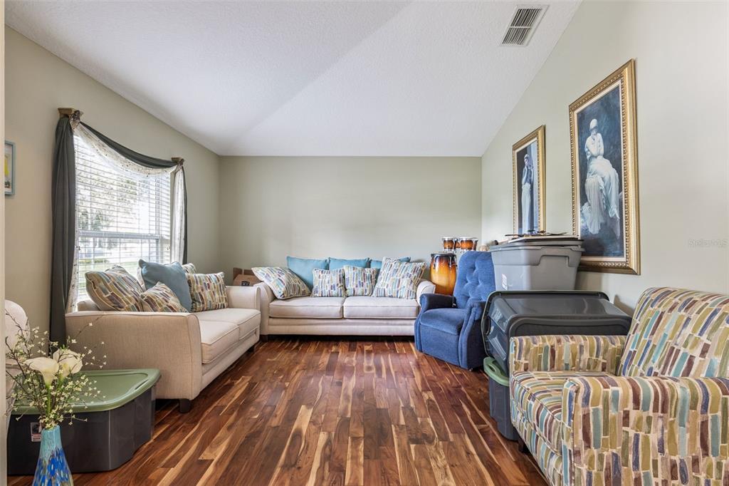 A living room with hardwood floors, two sofas, a recliner, and patterned accent chairs — 1545 OVERTON STREET, DELTONA, FL