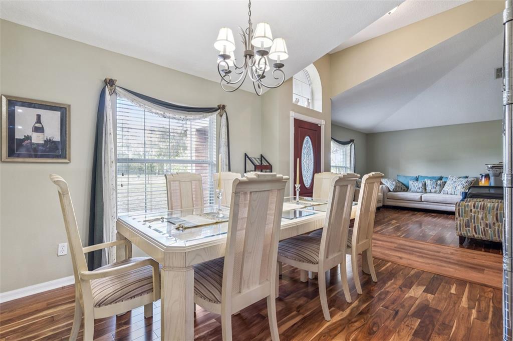A dining room with a glass-topped table, wooden chairs, and hardwood floors — 1545 OVERTON STREET, DELTONA, FL