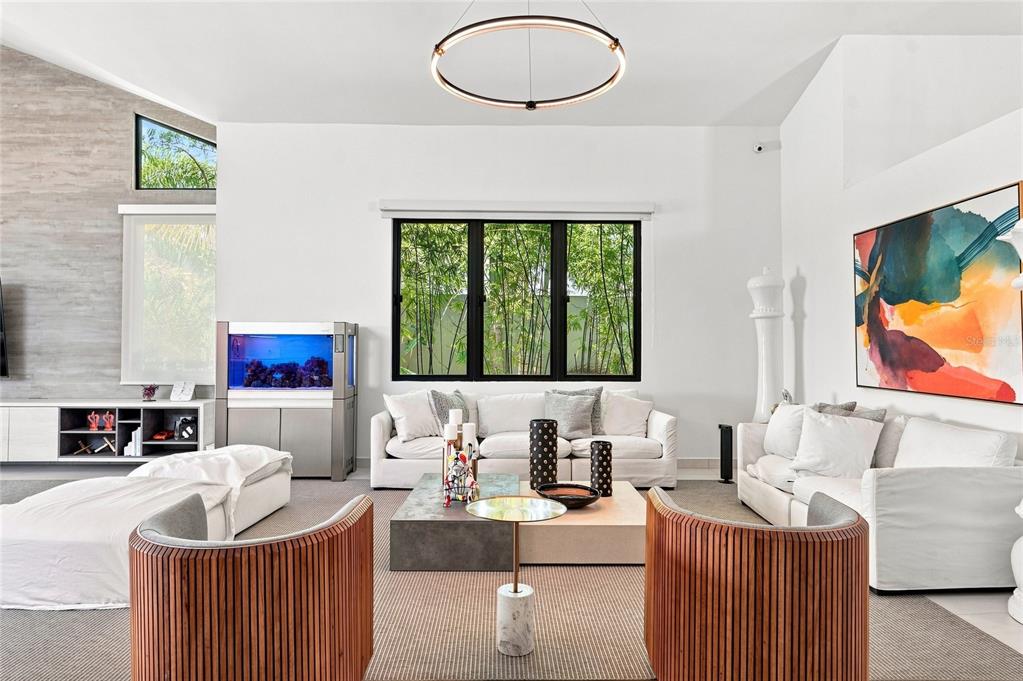 A modern living room features white sofas, wood-slatted chairs, a large aquarium, and a circular chandelier — 935 ISLA NORTE, DORADO, PR