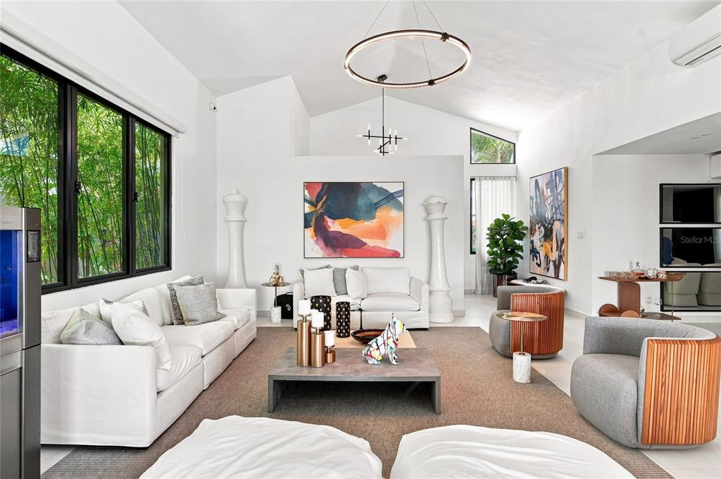 A bright living room features white sofas, gray armchairs, abstract art, and a large chandelier — 935 ISLA NORTE, DORADO, PR