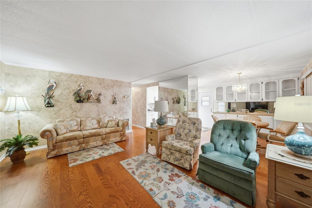 A living room with hardwood floors, floral furniture, and a mirrored wall divider — 3450 GRAPEFRUIT LANE, ESTERO, FL