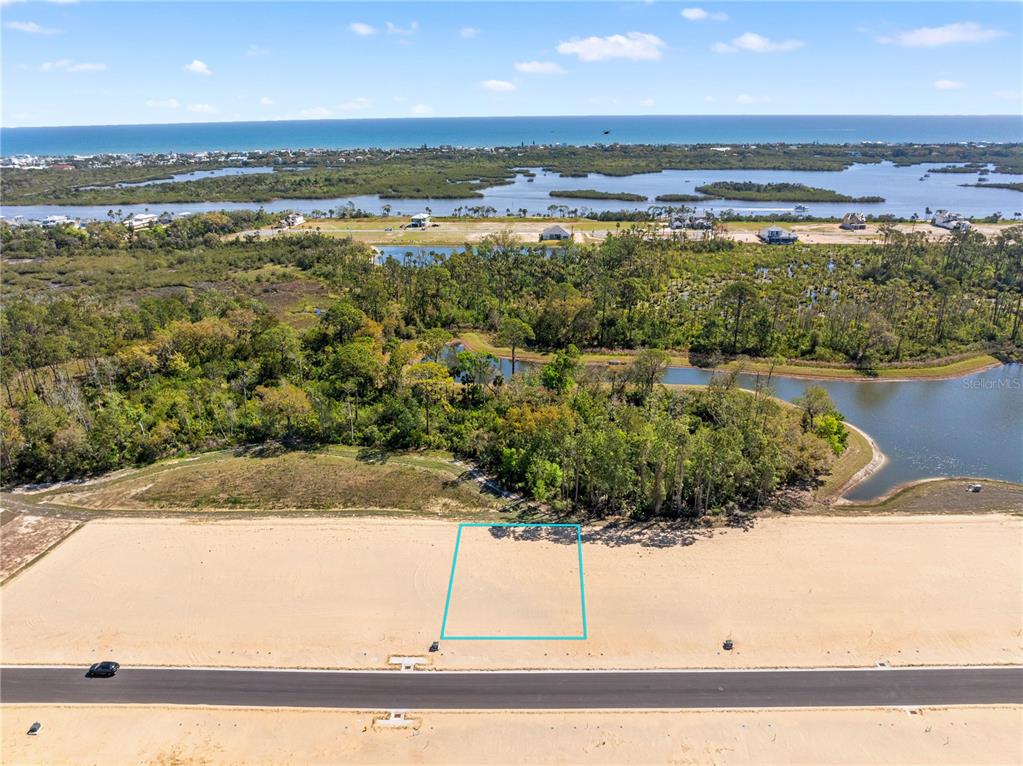 An aerial view shows a rectangular vacant lot outlined in blue along a paved road — 210 STILLWATER DRIVE, FLAGLER BEACH, FL