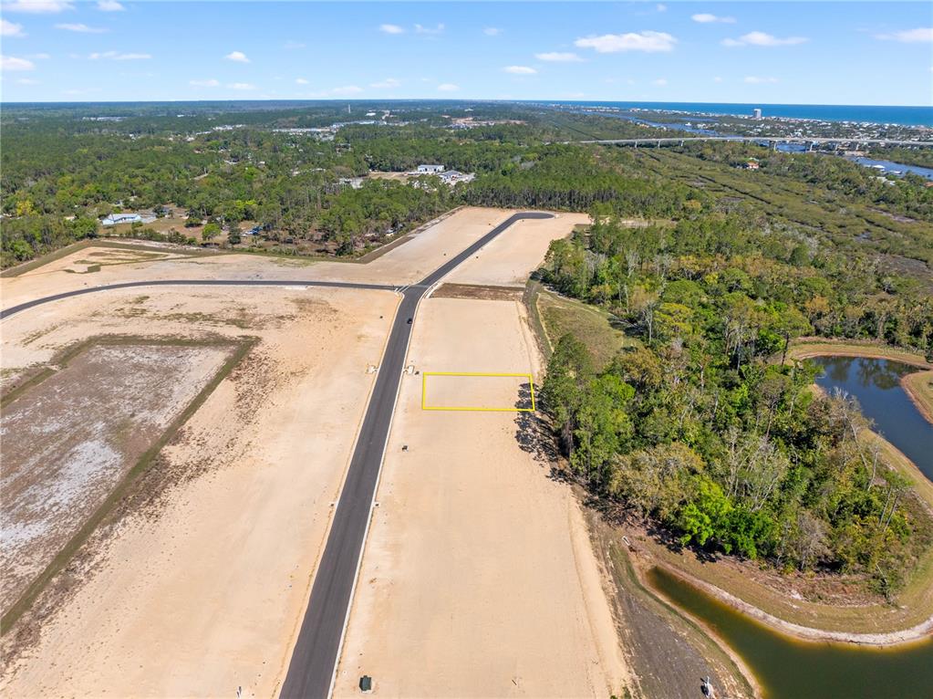 An aerial view shows a vacant residential lot outlined in yellow within a new subdivision — 210 STILLWATER DRIVE, FLAGLER BEACH, FL