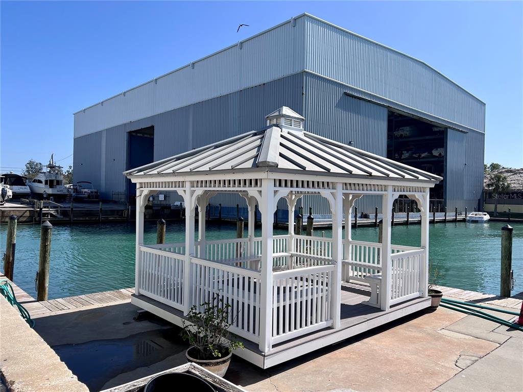A white gazebo with a metal roof sits on a concrete dock by the water — 100 CIRCUIT ROAD UNIT S70, NOKOMIS, FL