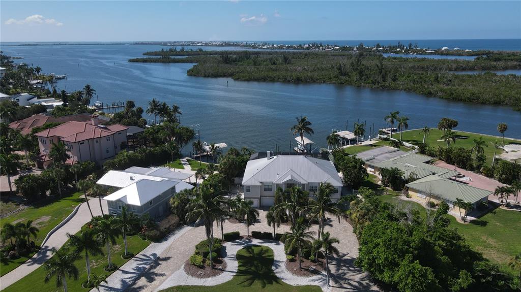 An aerial view shows several waterfront houses with palm trees and docks along a bay — 100 BUCCANEER BEND, PLACIDA, FL
