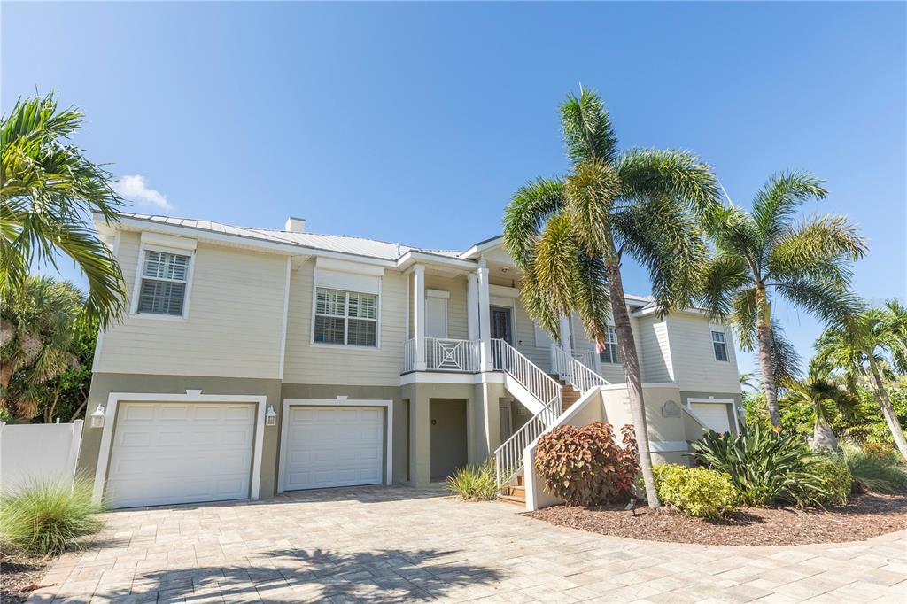 A two-story house with a paved driveway, two garage doors, and an elevated front entrance — 100 BUCCANEER BEND, PLACIDA, FL