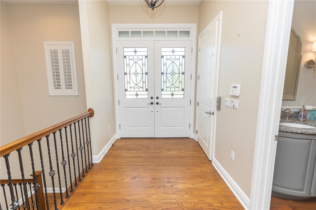 An entryway with hardwood floors, double front doors, a staircase railing, and a small bathroom — 100 BUCCANEER BEND, PLACIDA, FL