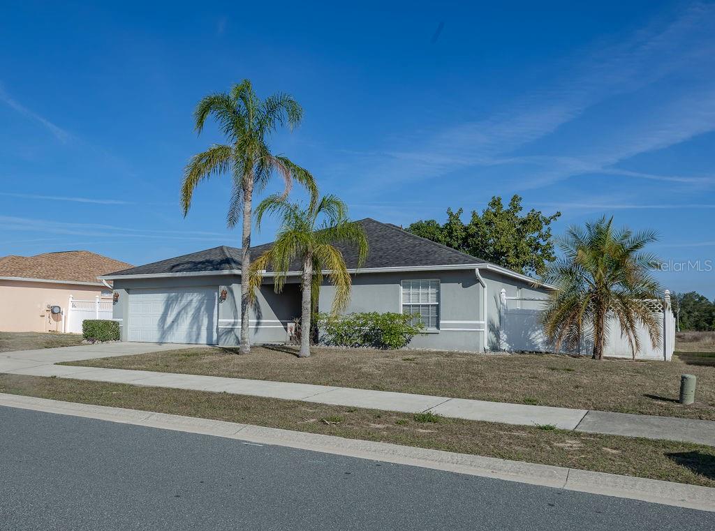 A single-story gray house with a two-car garage and palm trees in the front yard — 1015 HIGHLAND CREST CIRCLE, LAKE WALES, FL