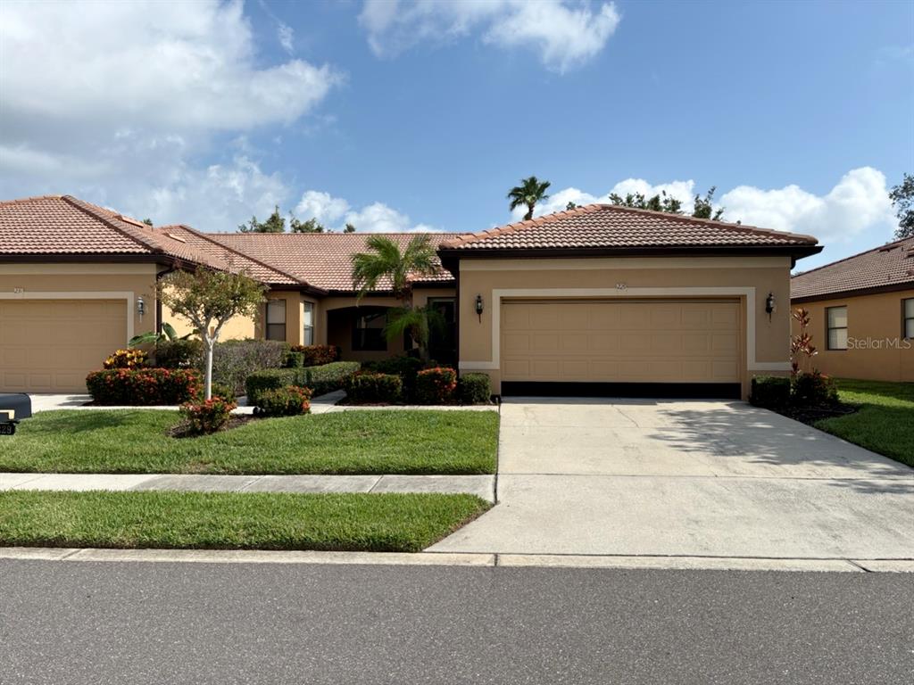 A single-story suburban house features a tan stucco exterior, a tiled roof, and a two-car garage — 229 SHELL FALLS DRIVE, APOLLO BEACH, FL