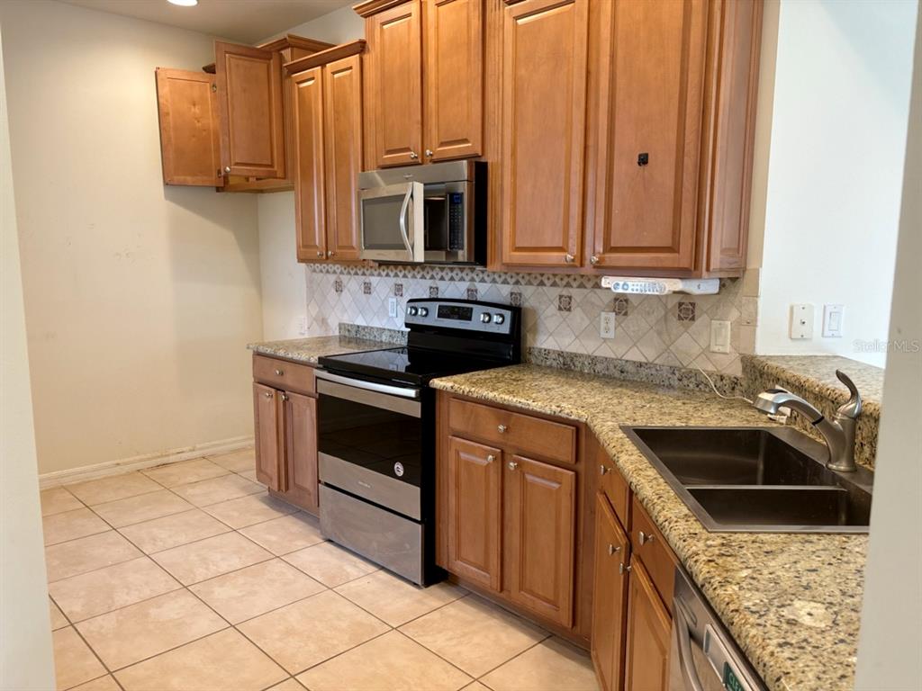 A kitchen with wood cabinets, granite countertops, stainless steel appliances, and tiled flooring — 229 SHELL FALLS DRIVE, APOLLO BEACH, FL