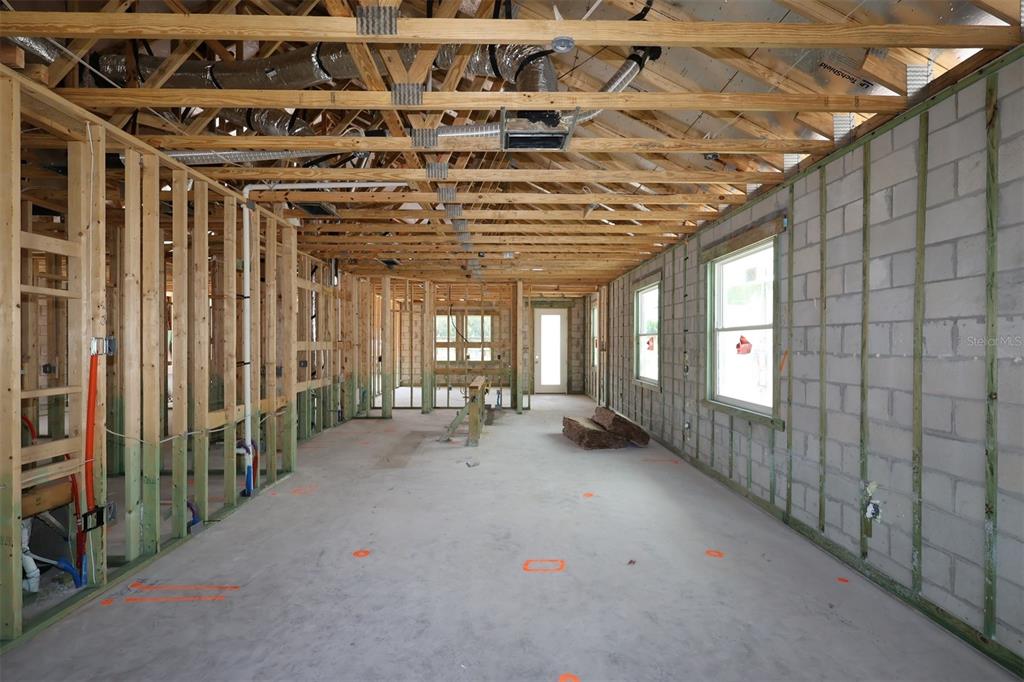 An unfinished interior space features exposed wood framing, concrete block walls, and open ceiling trusses — 2867 SWEETGRASS LANE, ZELLWOOD, FL