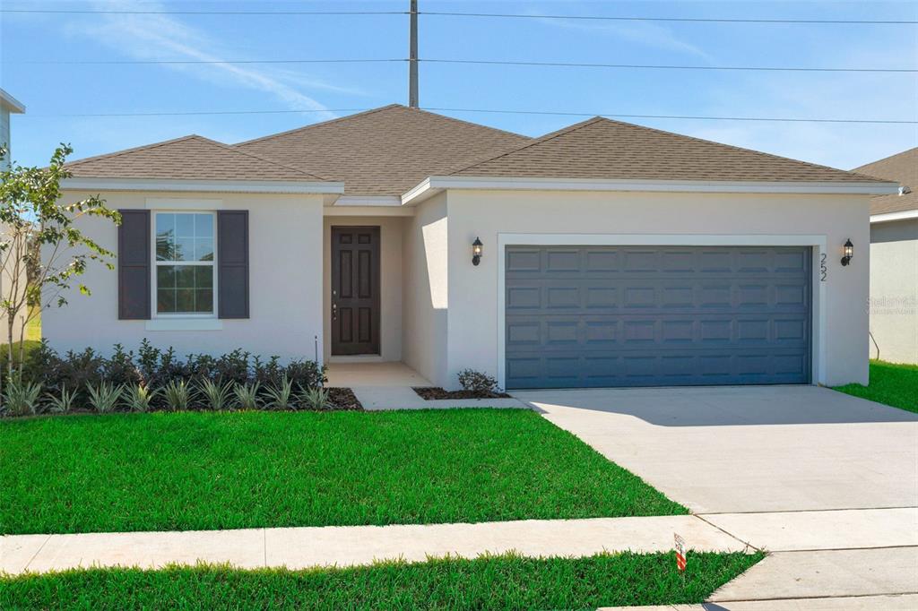 A single-story house with a light-colored stucco exterior, a dark front door, and a garage — 300 MEREDITH BOULEVARD, WINTER HAVEN, FL