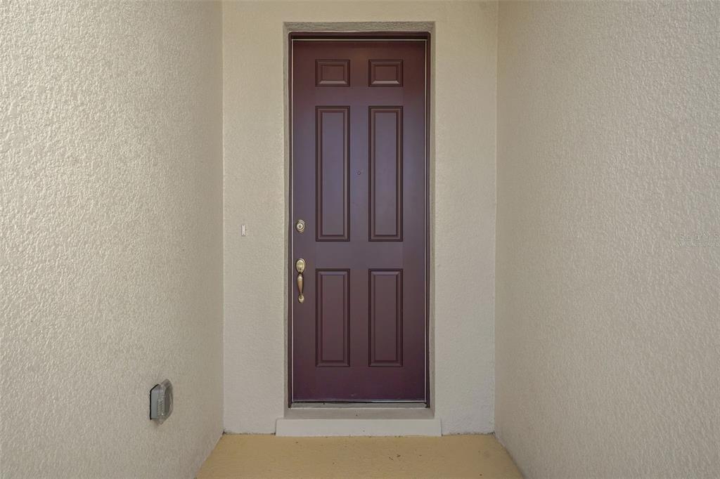 A dark purple six-panel front door is set within a recessed entryway with beige walls — 300 MEREDITH BOULEVARD, WINTER HAVEN, FL