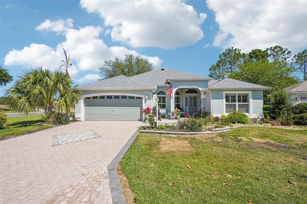 A light blue house exterior features a paved patio, a front door, and potted flowers — 2837 GRANT WAY, THE VILLAGES, FL