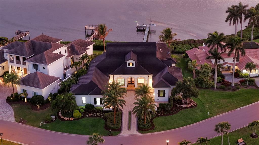An aerial view shows a large waterfront house with a dark roof and palm trees — 313 LOOKOUT POINT DRIVE, OSPREY, FL