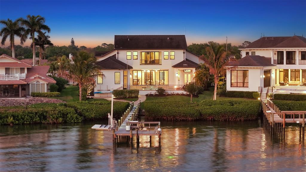 An exterior view of a waterfront house with a private dock at dusk — 313 LOOKOUT POINT DRIVE, OSPREY, FL