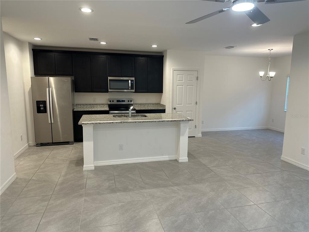 A kitchen features dark cabinets, stainless steel appliances, granite countertops, and a central island — 189 GLASS ONION DRIVE, GROVELAND, FL