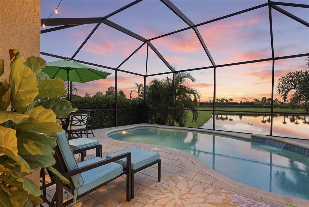 A screened-in patio features a swimming pool, patio furniture, and a view of a lake — 16120 SUNNY DAY DRIVE, BRADENTON, FL
