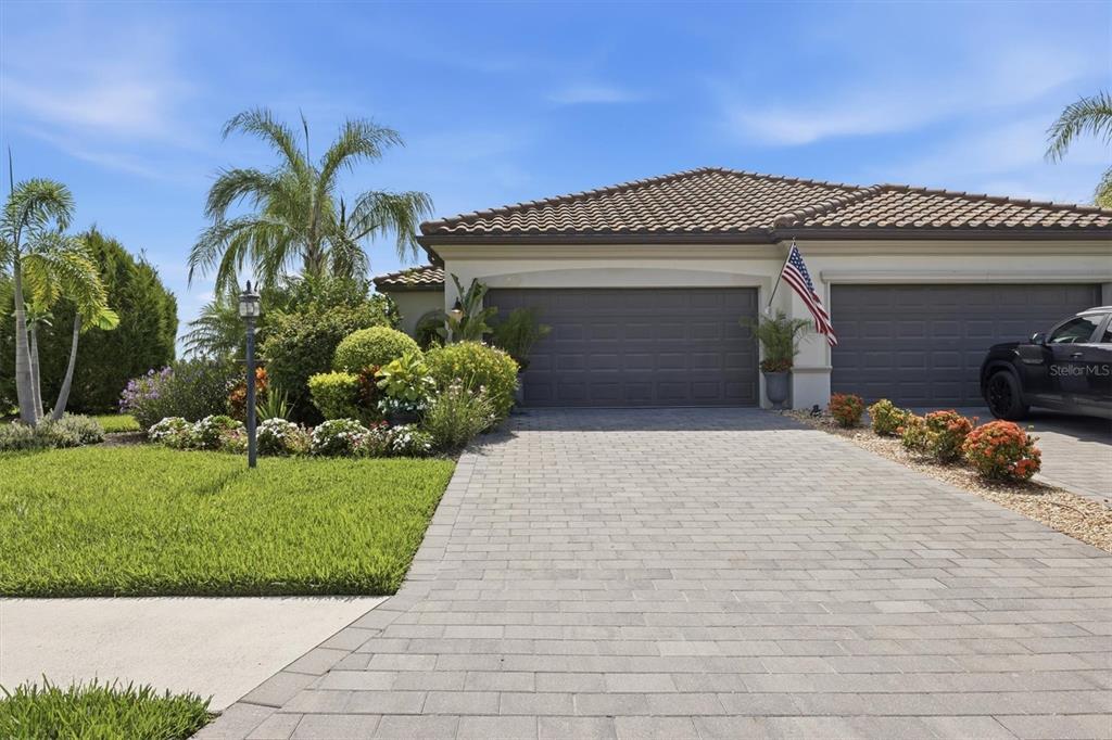 A paved driveway leads to a two-car garage of a house with a tiled roof — 16120 SUNNY DAY DRIVE, BRADENTON, FL