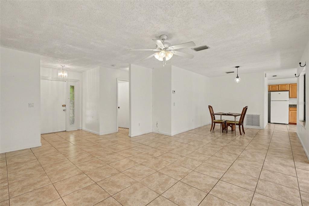 An open-concept living and dining area features white walls, tile flooring, and a ceiling fan — 997 MARIPOSA DRIVE NE, PALM BAY, FL