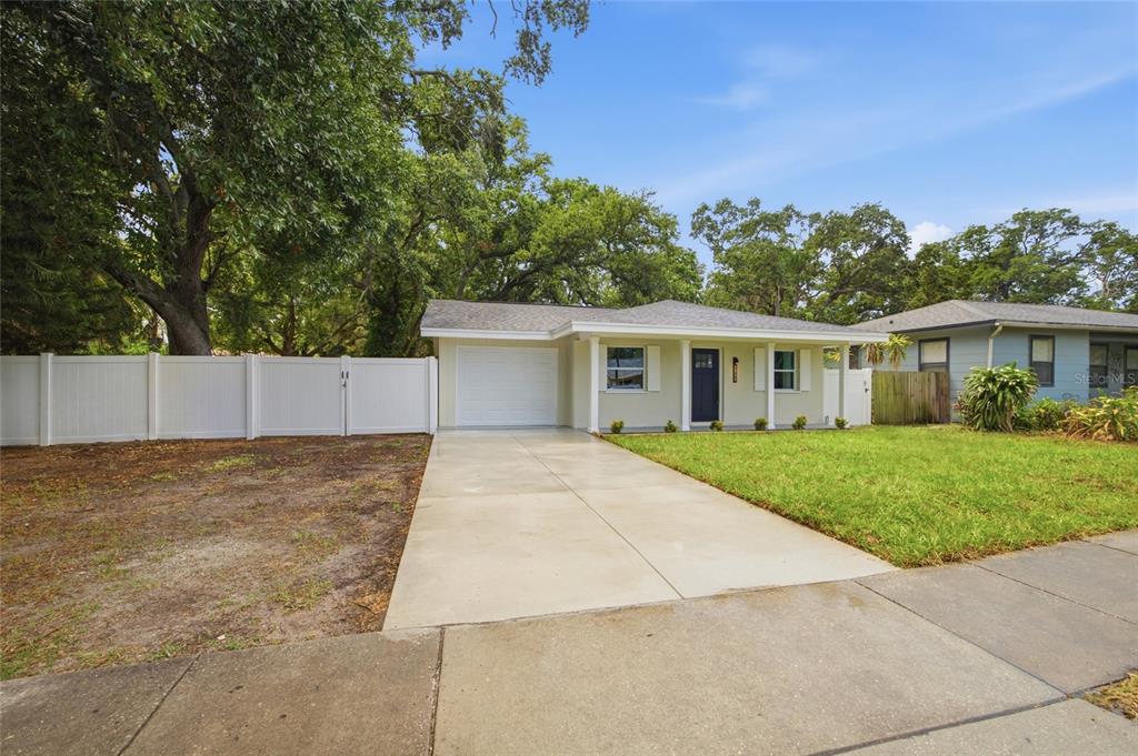 A single-story house with a white garage, a concrete driveway, and a white privacy fence — 1333 OVERLEA STREET, CLEARWATER, FL