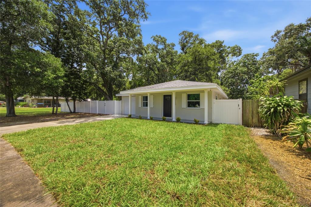A single-story house with a light-colored exterior, a front porch, and a white vinyl fence — 1333 OVERLEA STREET, CLEARWATER, FL