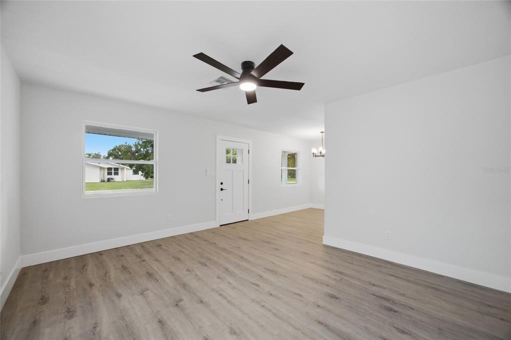 A living room features light gray walls, wood-look flooring, a ceiling fan, and a front door — 1333 OVERLEA STREET, CLEARWATER, FL