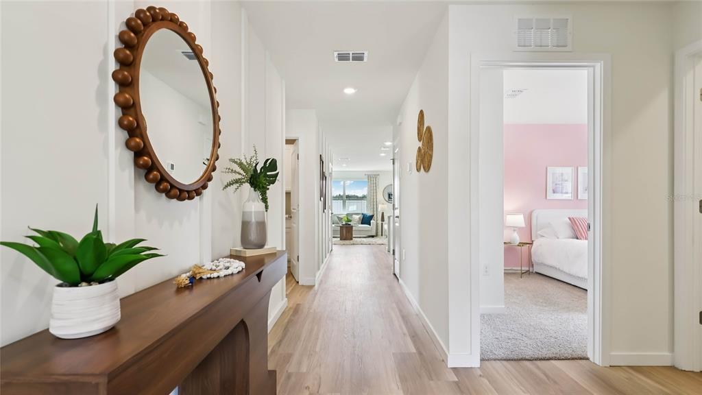 A hallway with light wood floors leads to a living area, with a bedroom visible — 10189 SE 158TH LANE, SUMMERFIELD, FL
