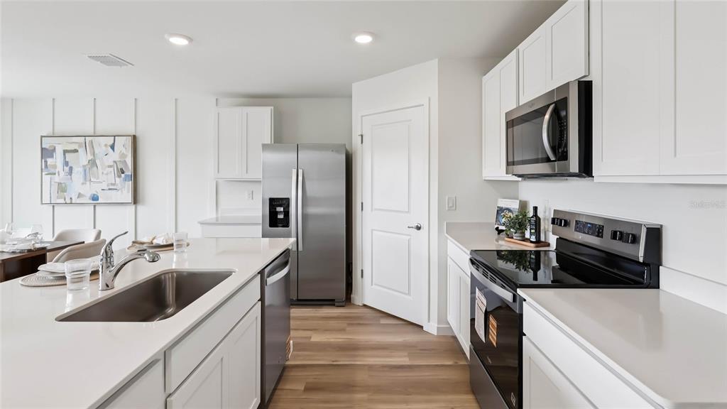 A modern kitchen features white cabinets, stainless steel appliances, and a large island with sink — 10189 SE 158TH LANE, SUMMERFIELD, FL