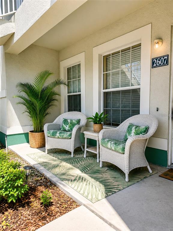 A patio features two white wicker chairs with green palm-print cushions and a potted palm — 2607 RIVER PRESERVE COURT UNIT 2607, BRADENTON, FL