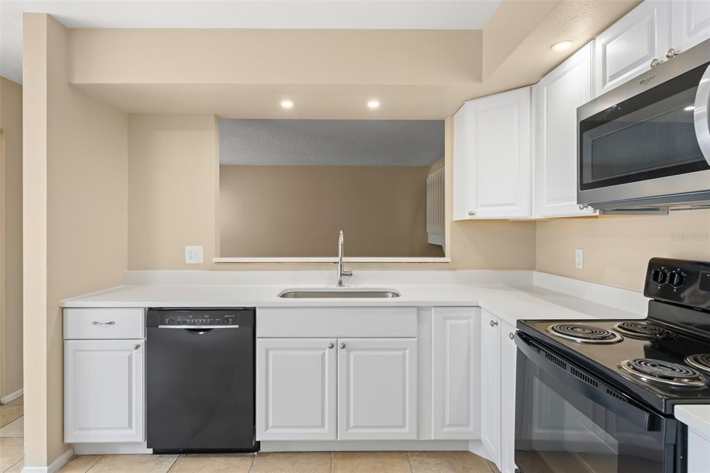 A two-story building features a screened balcony above three garage doors and parked cars — 4623 RING NECK ROAD UNIT B-1, ORLANDO, FL