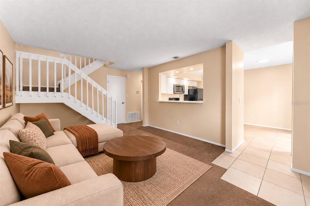 A concrete patio sits outside a two-story building with green siding and a privacy fence — 4623 RING NECK ROAD UNIT B-1, ORLANDO, FL