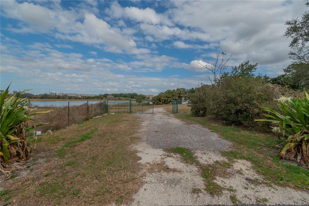 A gravel path leads toward a gated chain-link fence overlooking a body of water — 4950 COUNTY ROAD 46A, SANFORD, FL