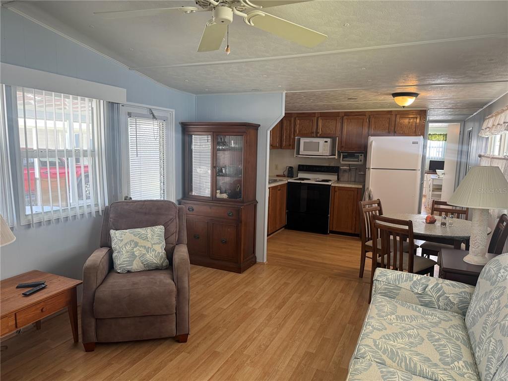 A living room with wood-look flooring flows into a kitchen with wood cabinets and appliances — 731 CAMELLIA DRIVE, VENICE, FL