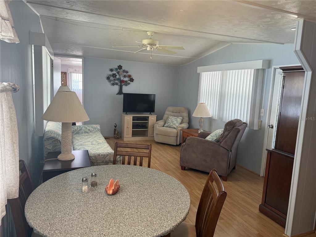 A living room and dining area feature light wood flooring, a ceiling fan, and furniture — 731 CAMELLIA DRIVE, VENICE, FL