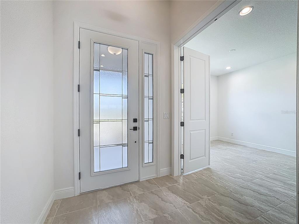 A bright entryway features a glass-paneled front door, tiled floors, and an adjacent open room — 4214 SEA MARSH PLACE, PARRISH, FL