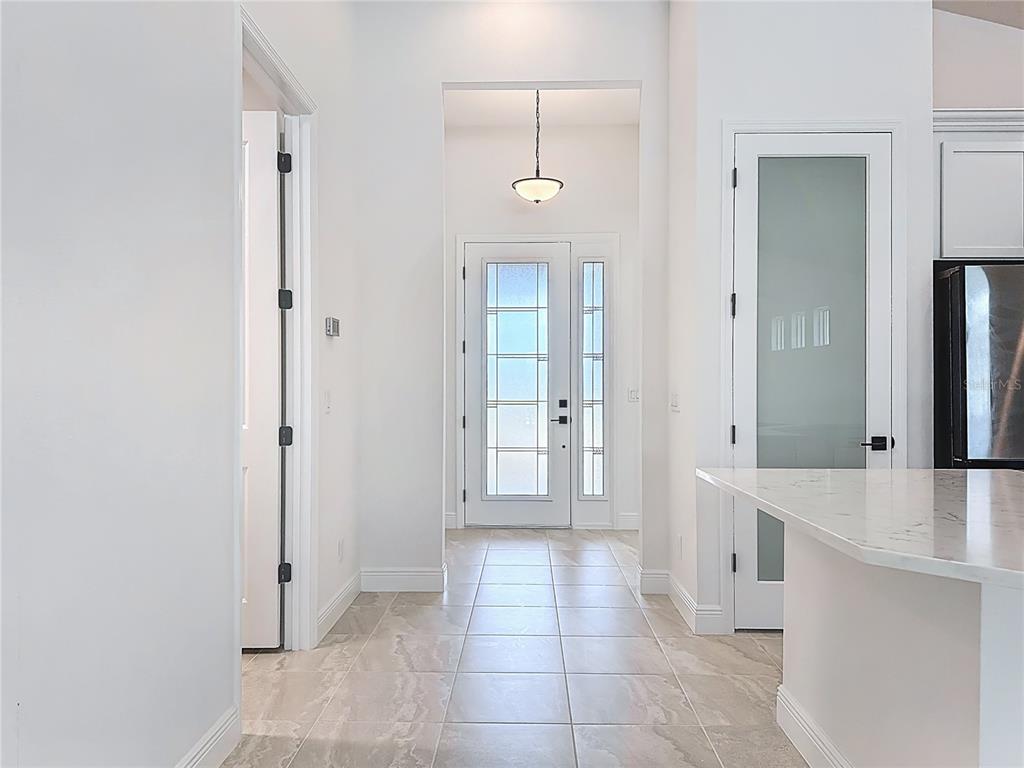 A bright entryway features tiled flooring, a glass-paneled front door, and a modern pendant light — 4214 SEA MARSH PLACE, PARRISH, FL