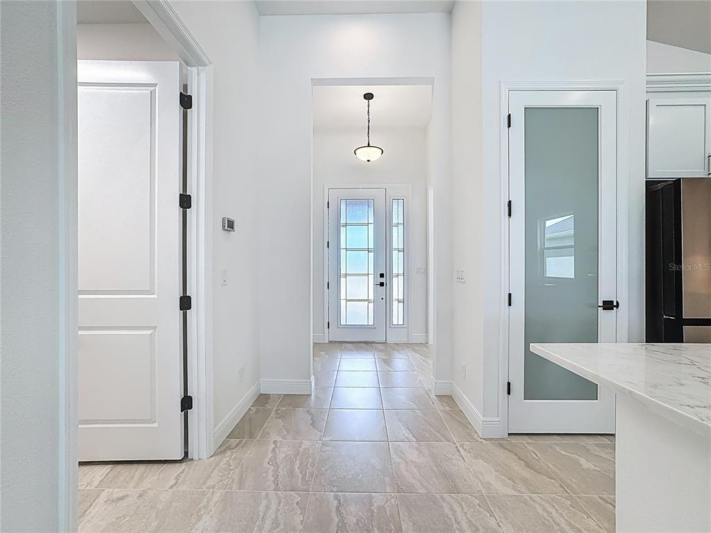 A tiled hallway leads to a front door with glass panels and a pendant light — 4214 SEA MARSH PLACE, PARRISH, FL