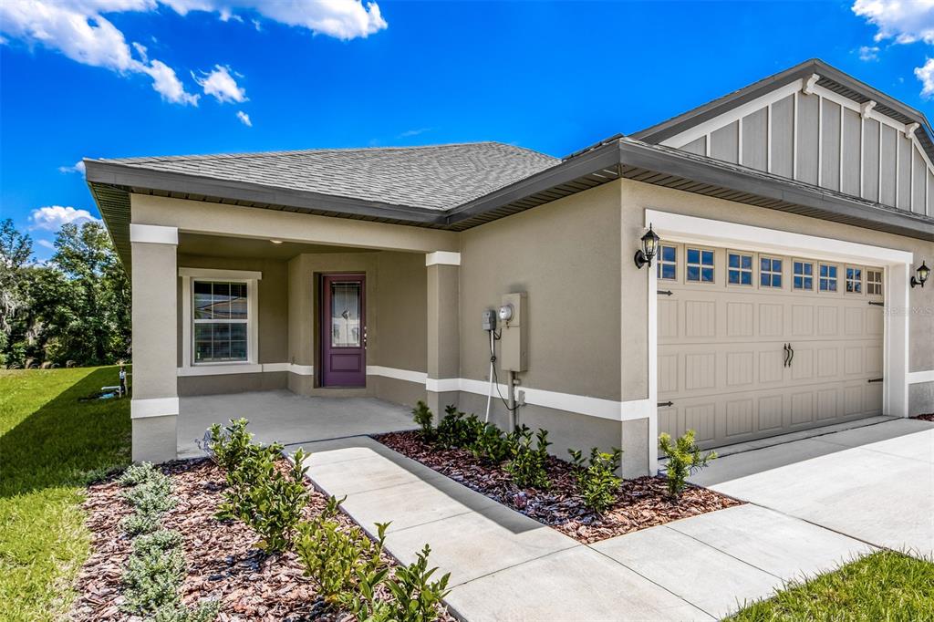 A single-story house exterior features a beige stucco facade, a purple front door, and garage — 3180 SEVILLE STREET, LAKE ALFRED, FL