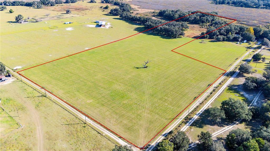 An aerial view shows a large, grassy, rectangular plot of land outlined in red — SW 60TH AVE, BUSHNELL, FL