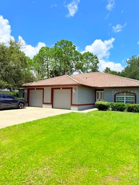 A single-story house with a two-car garage and a tiled roof sits on a lawn — 5 PONTIAC LANE UNIT B, PALM COAST, FL