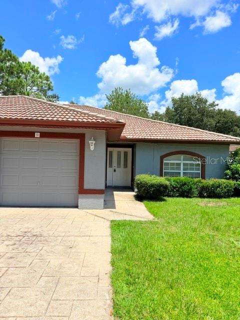 A single-story house features a gray exterior, a tiled roof, and a paved driveway — 5 PONTIAC LANE UNIT B, PALM COAST, FL