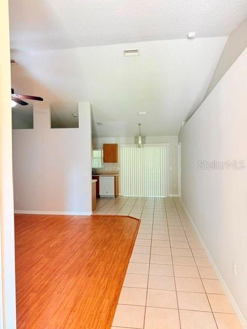 An open-concept living area features wood-look flooring, tiled kitchen space, and a vaulted ceiling — 5 PONTIAC LANE UNIT B, PALM COAST, FL